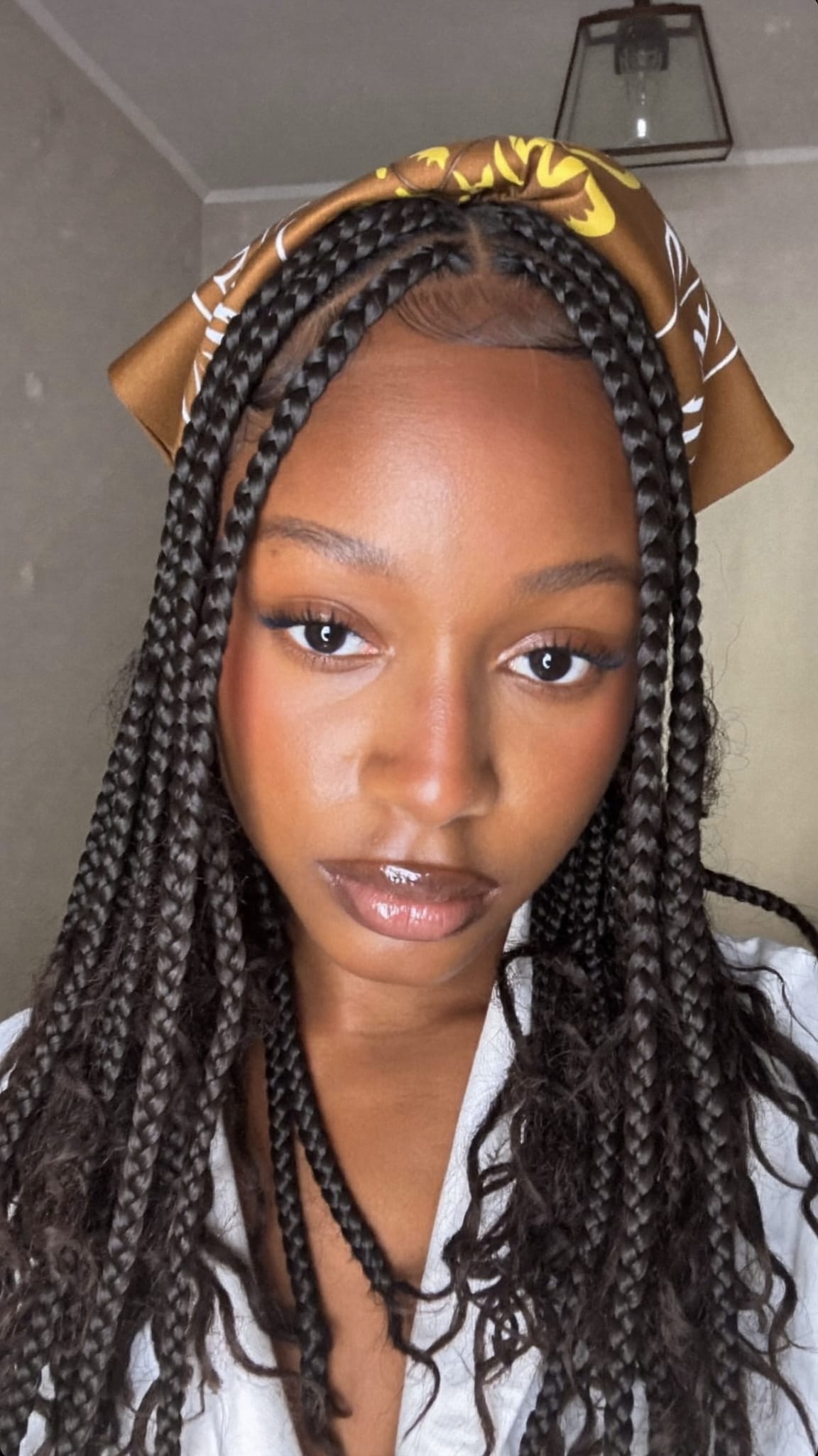 Black woman with long box braids wearing a silk square bandana as a headband