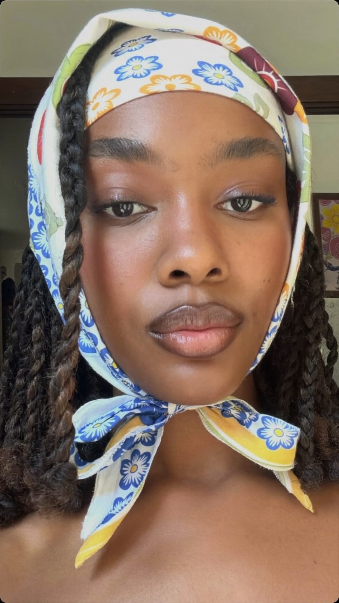 Black woman with medium knotless braids wearing a floral cotton bandana tied in a bow at the nape