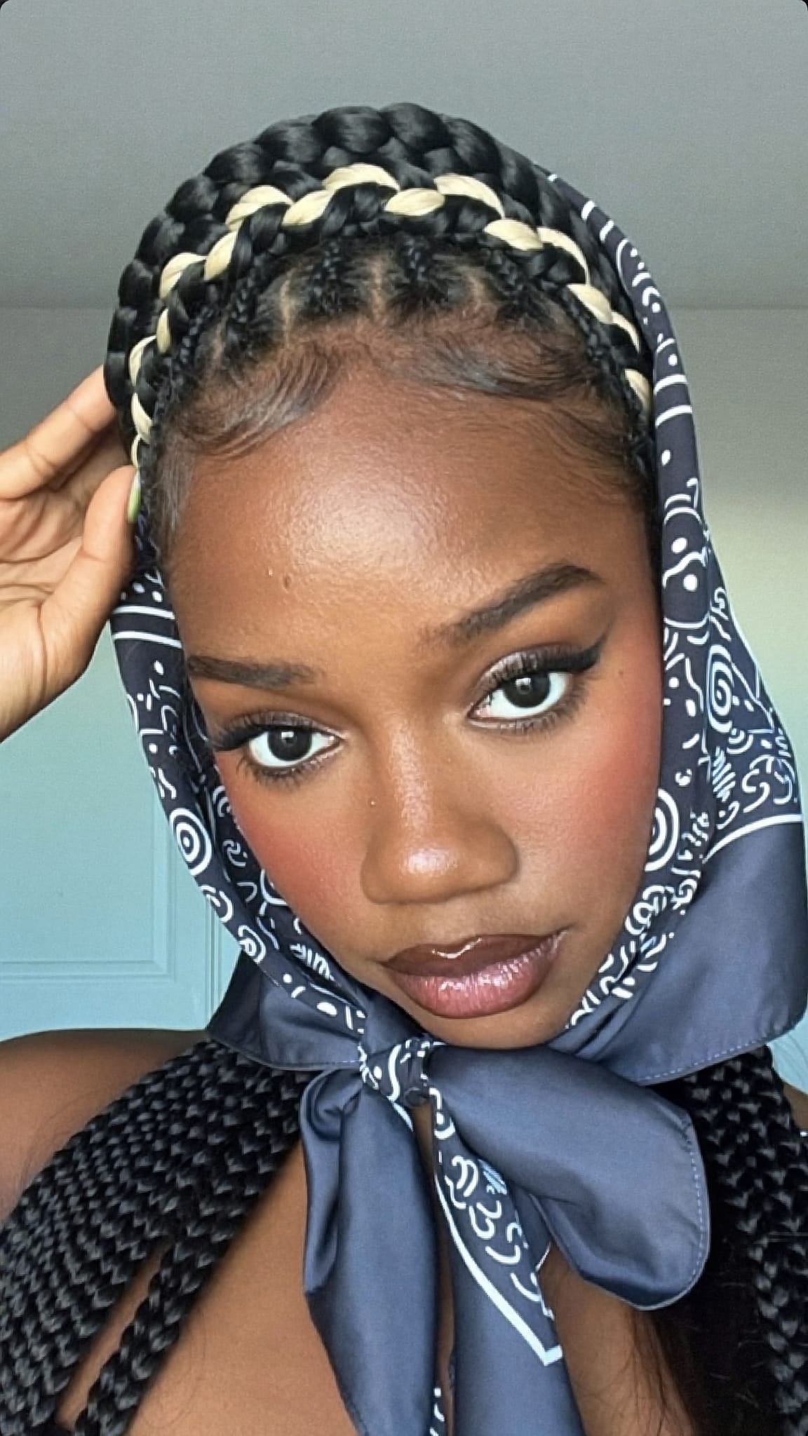 Black woman with a braided crown halo style wearing a thin satin bandana woven through the crown braid