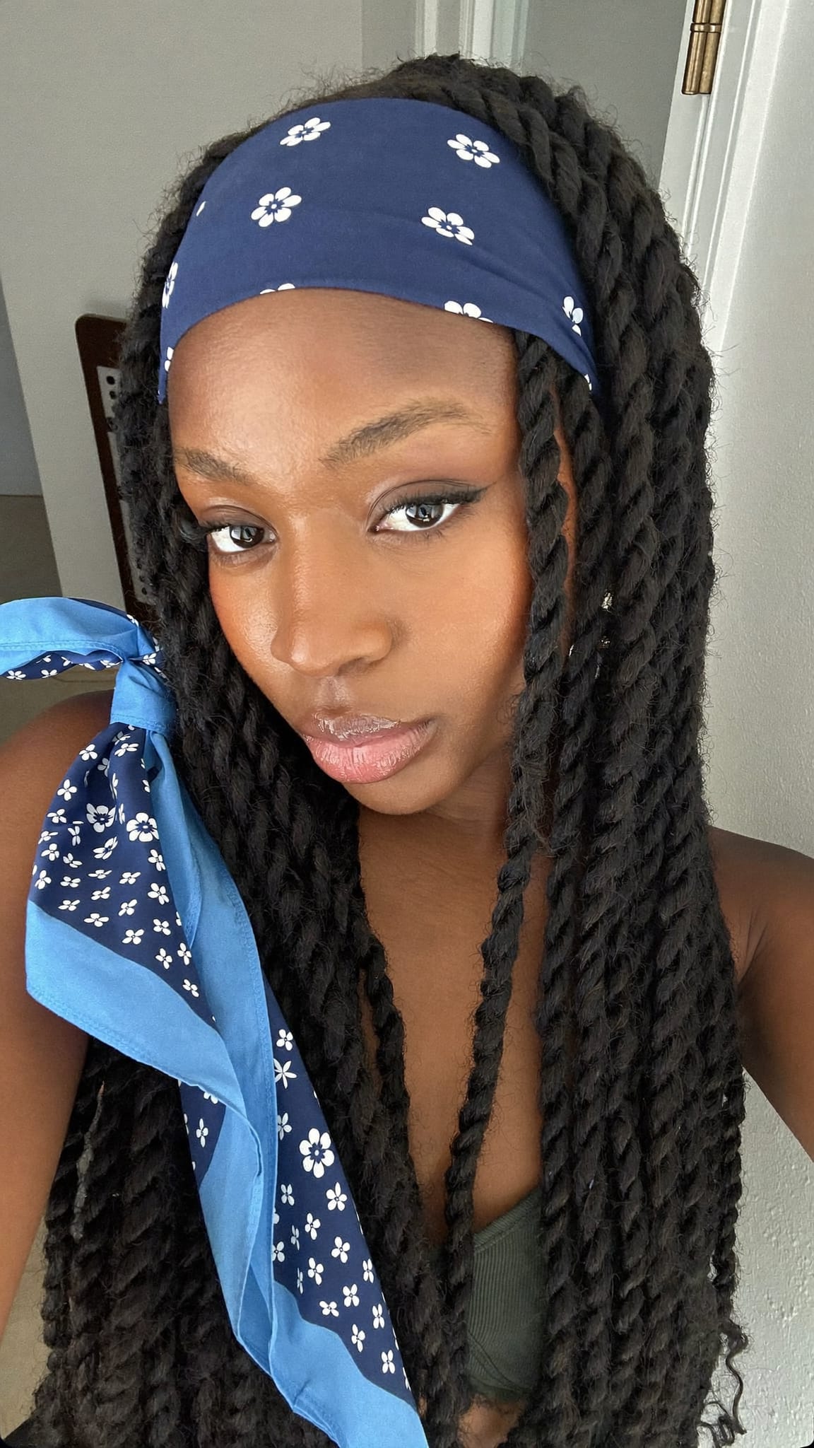 Black woman with two-strand twists wearing a navy blue floral printed square bandana as a headband