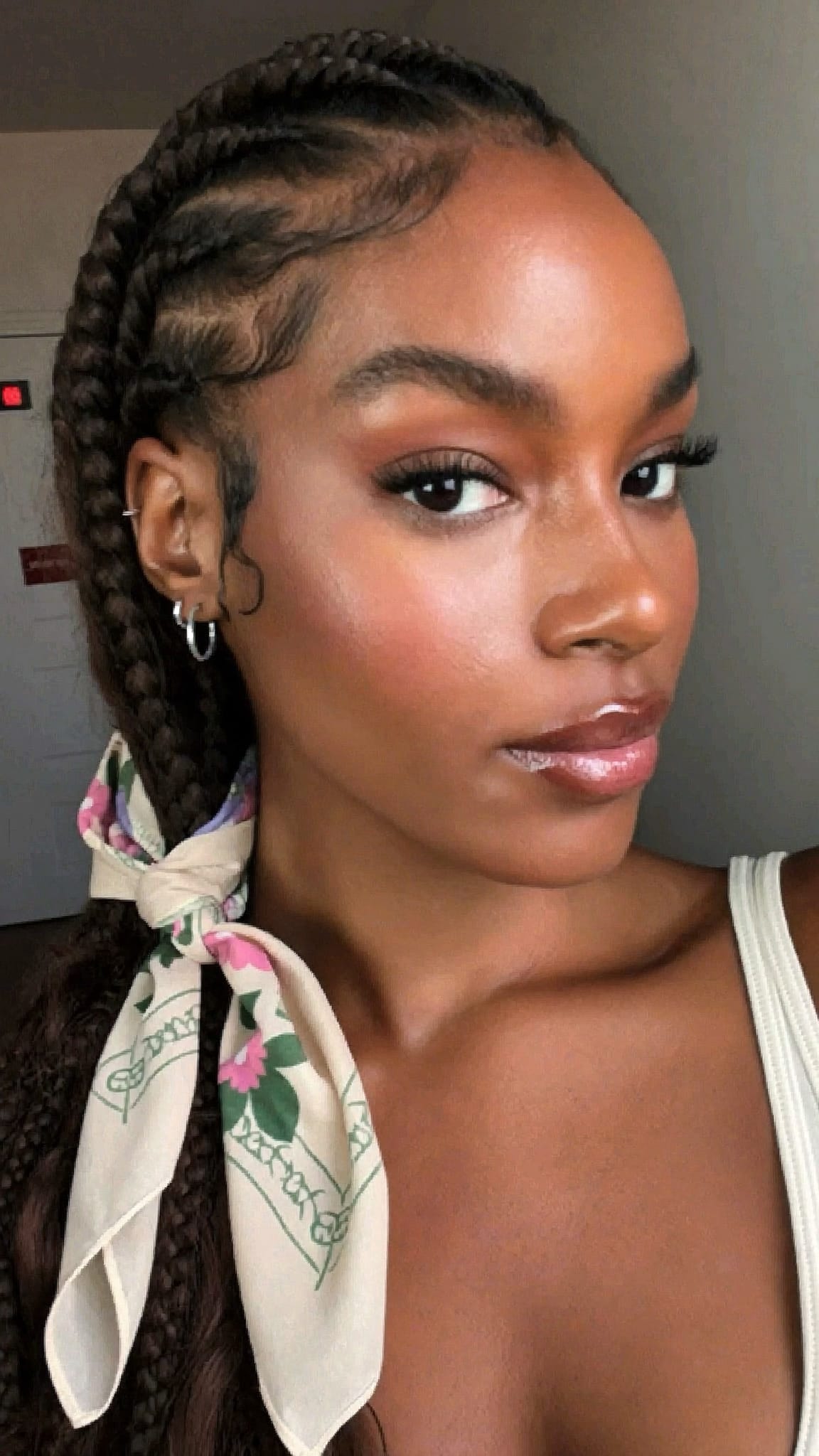 Black woman with side-swept cornrows on one side and a floral bandana tied as an accent on the cornrowed side