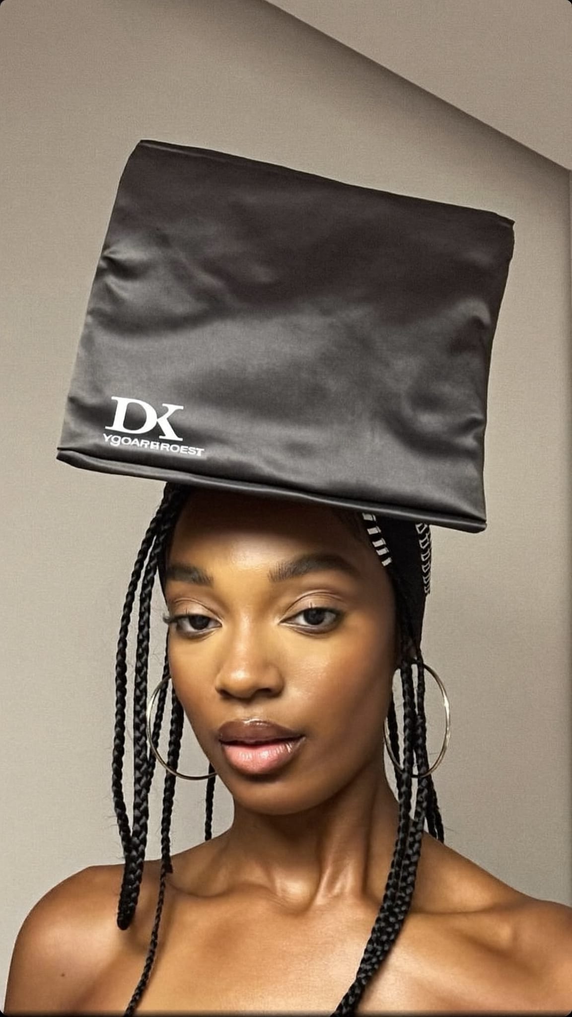 Black woman with micro braids wearing a large satin square bandana as a full head wrap with braids falling below