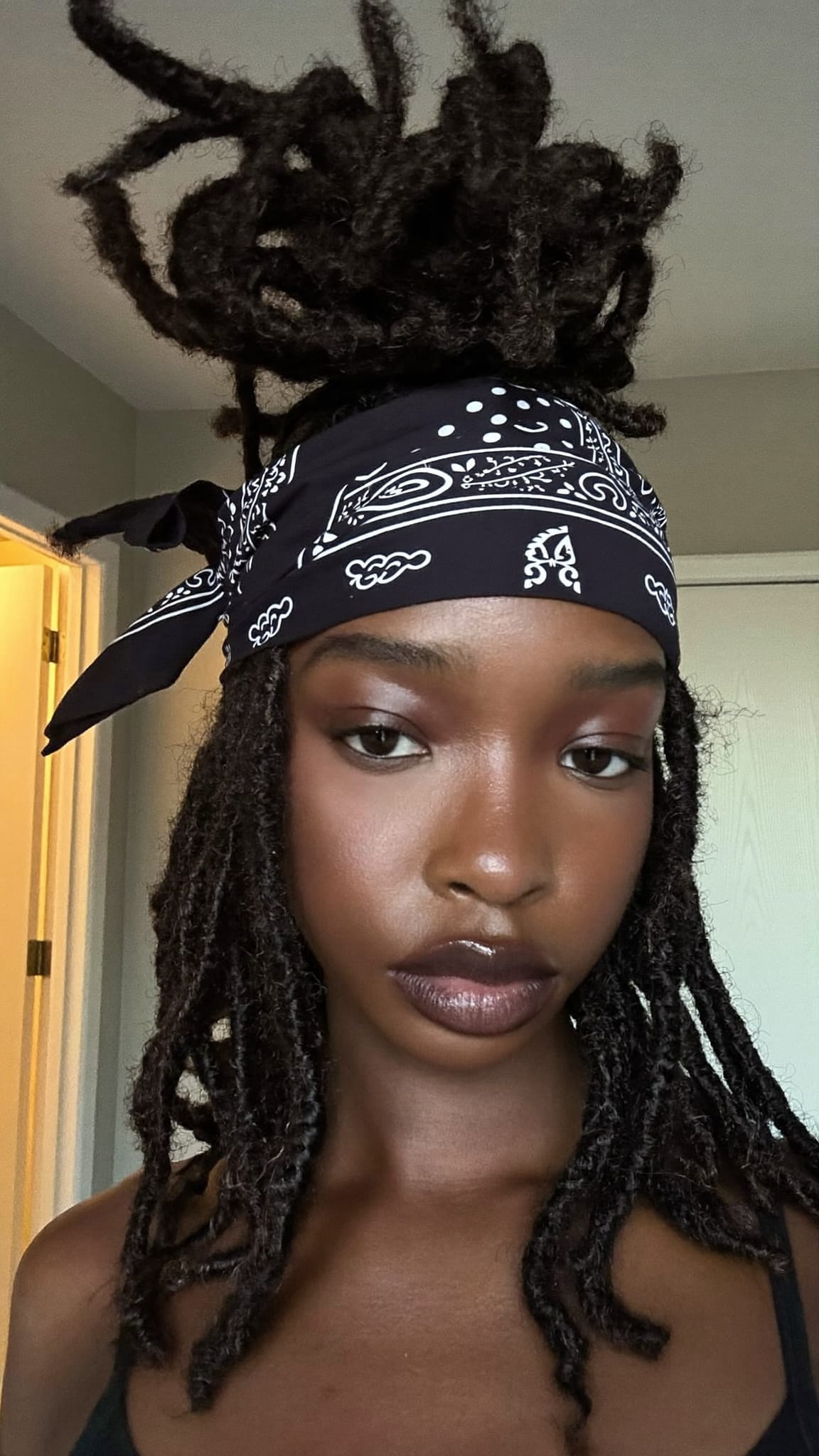 Black woman with voluminous butterfly locs wearing a paisley bandana tied as a headband across the front