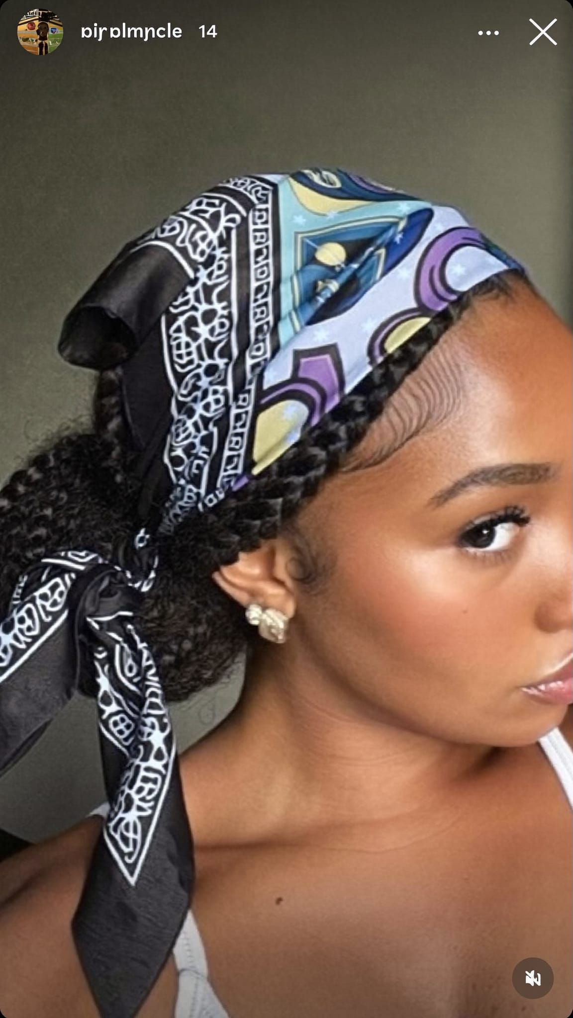 Black woman with chunky braids styled in a low bun wearing a large satin silk bandana tied in a dramatic bow at the bun