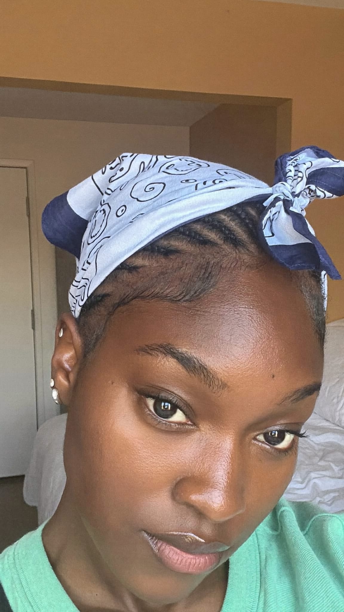 Black woman with tight straight-back cornrows wearing a printed cotton bandana tied over the top in a do-rag style