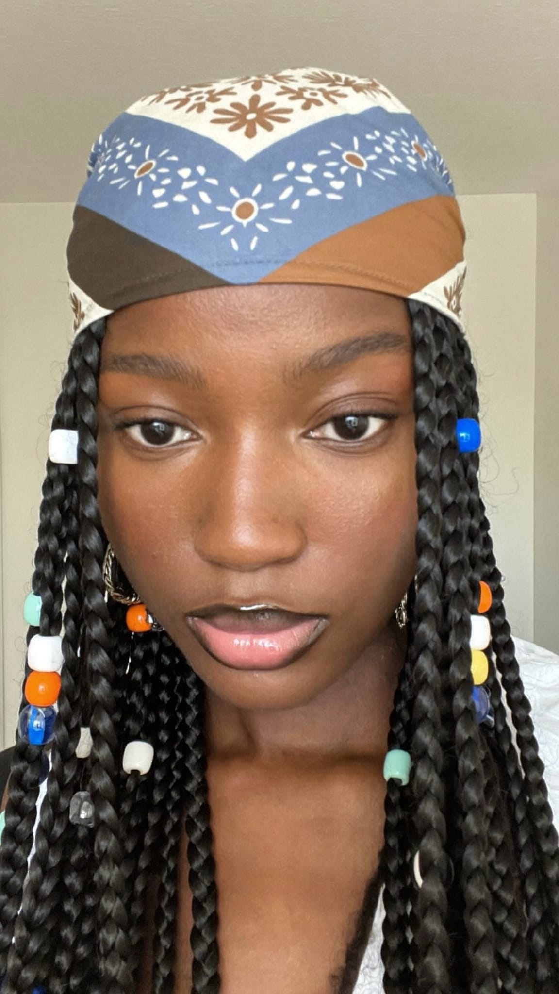 Black woman with Fulani braids featuring beads wearing a floral boho triangle bandana as a forehead accent