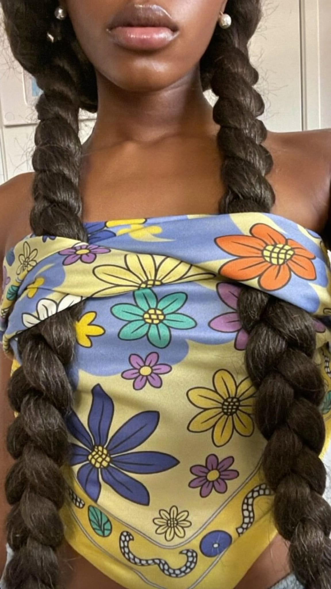 Black woman with thick jumbo box braids wearing a large satin silk floral bandana wrapped around the braids mid-length like a belt