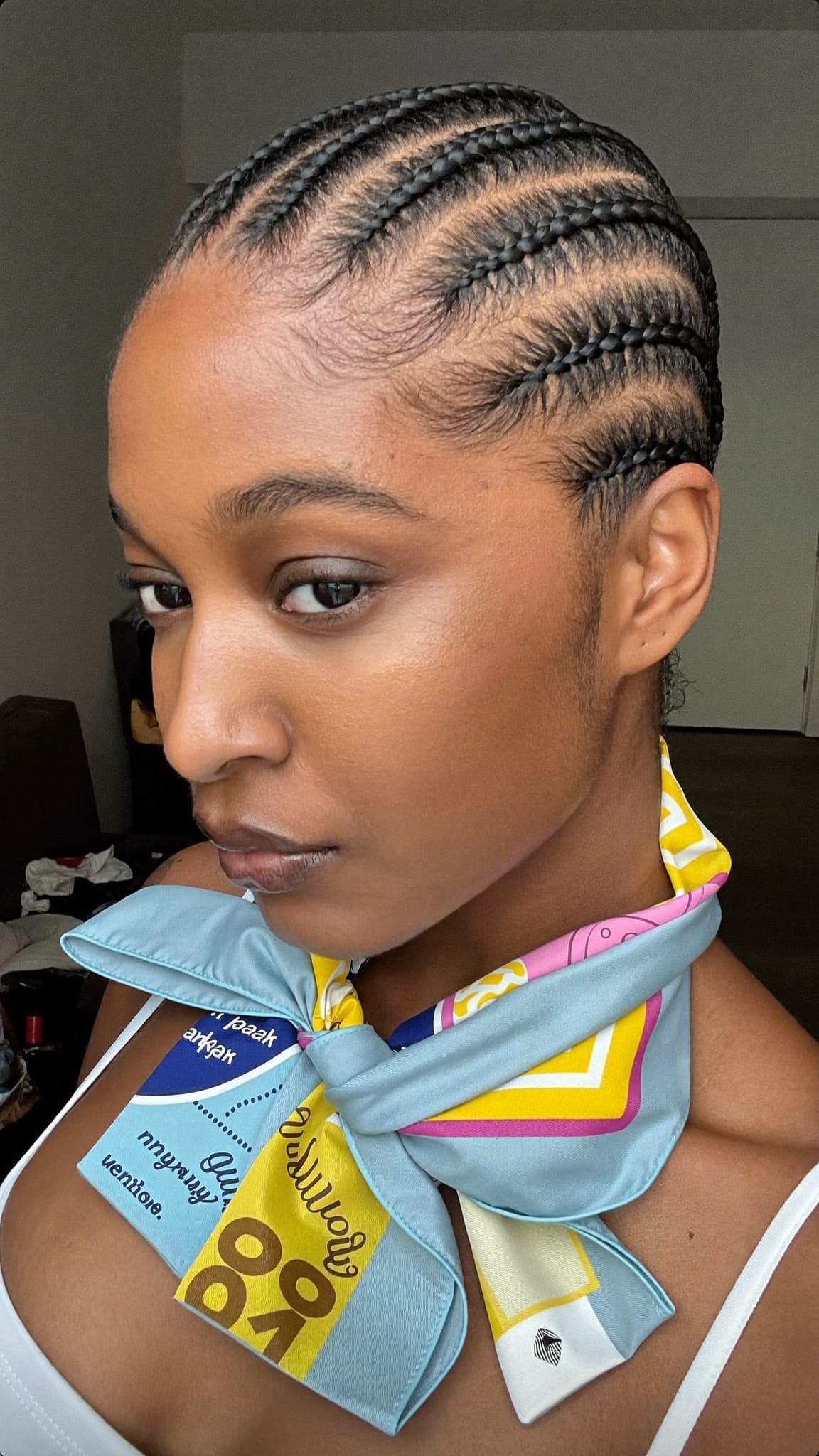 Black woman with neat feed-in cornrows wearing a 4-pack satin bandana tied at the front as a finishing accent