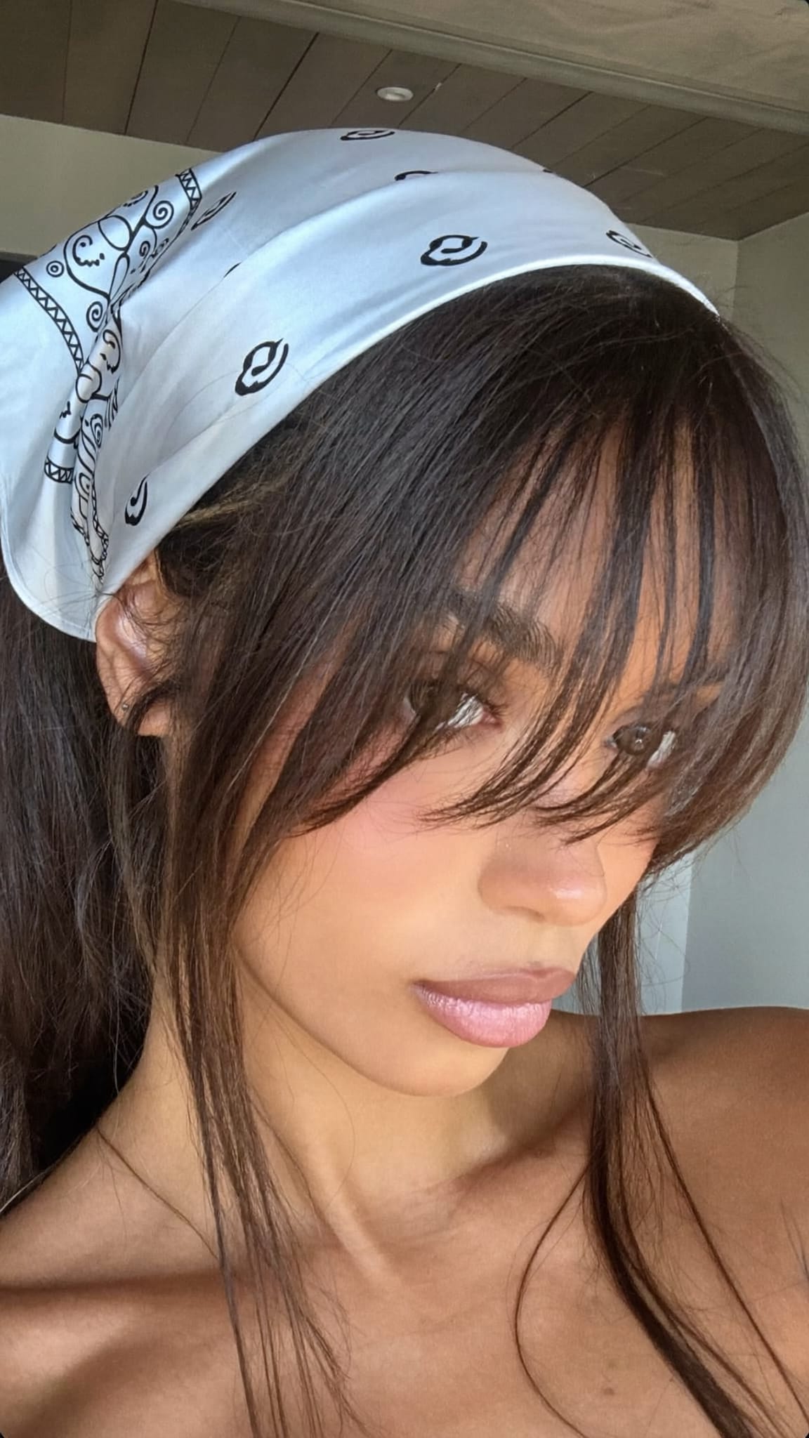 Latina woman with grown-out awkward-length bangs wearing a satin bandana headband that pushes the bangs back and off the face