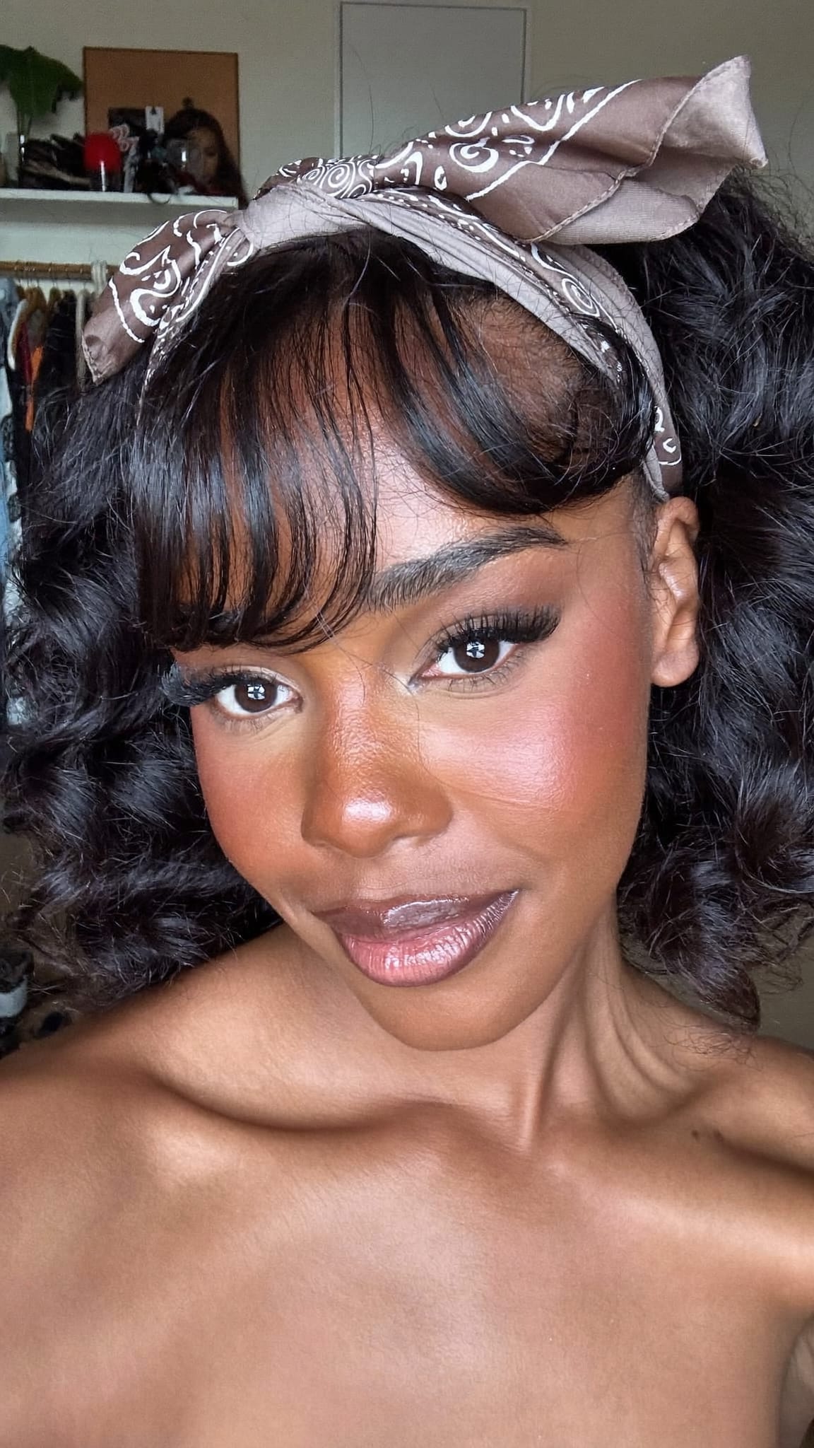 Black woman with voluminous curtain bangs wearing a paisley elastic knot bandana headband just behind her parted fringe