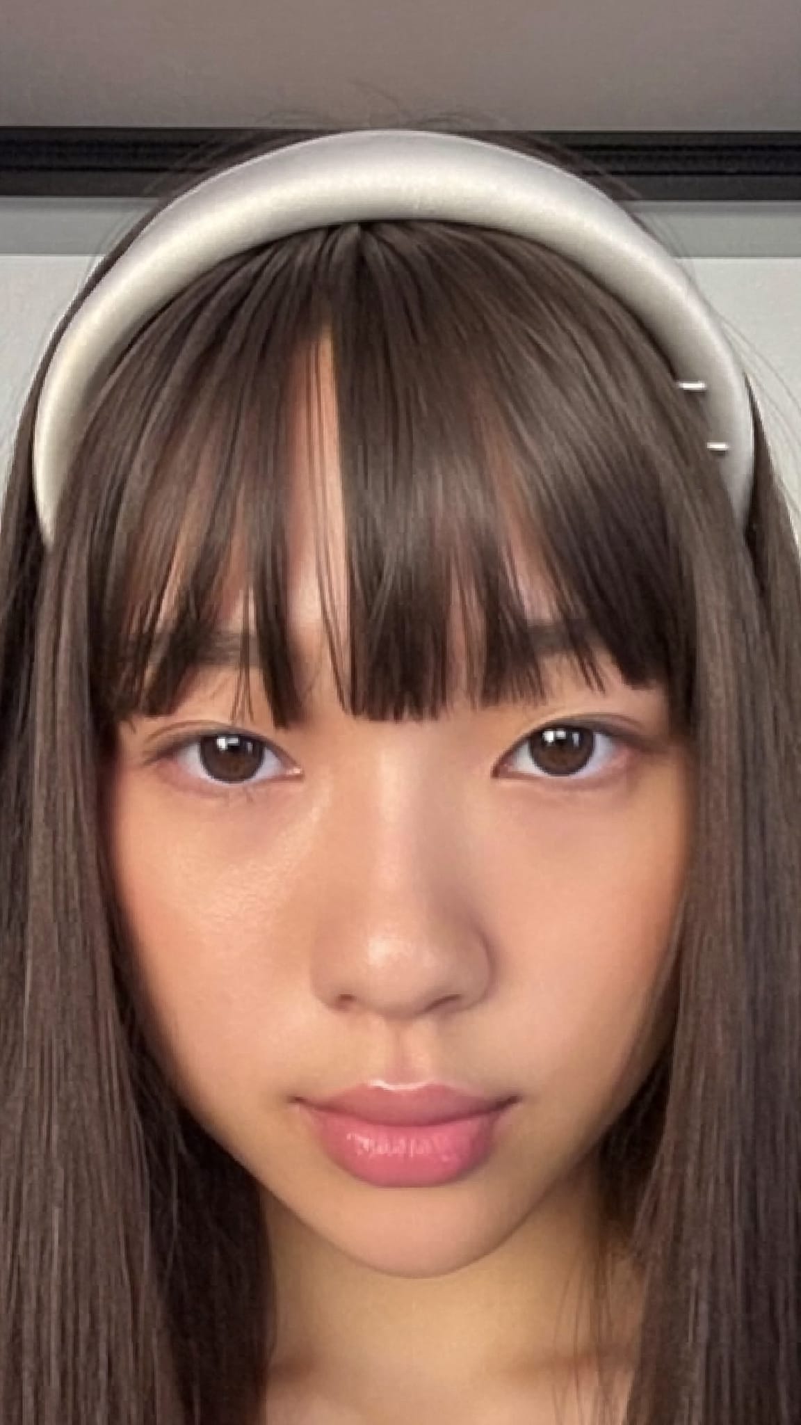 East Asian woman with thick straight-across Asian bangs wearing a narrow silk satin headband positioned just at the bang line