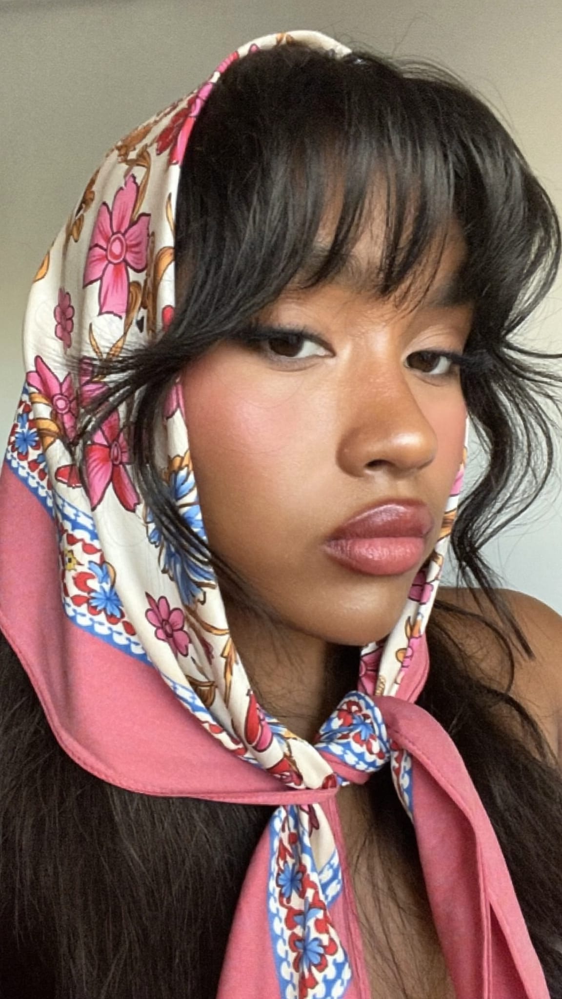 South Asian woman with textured wavy curtain bangs wearing a vintage silk satin bandana in a half-wrap style