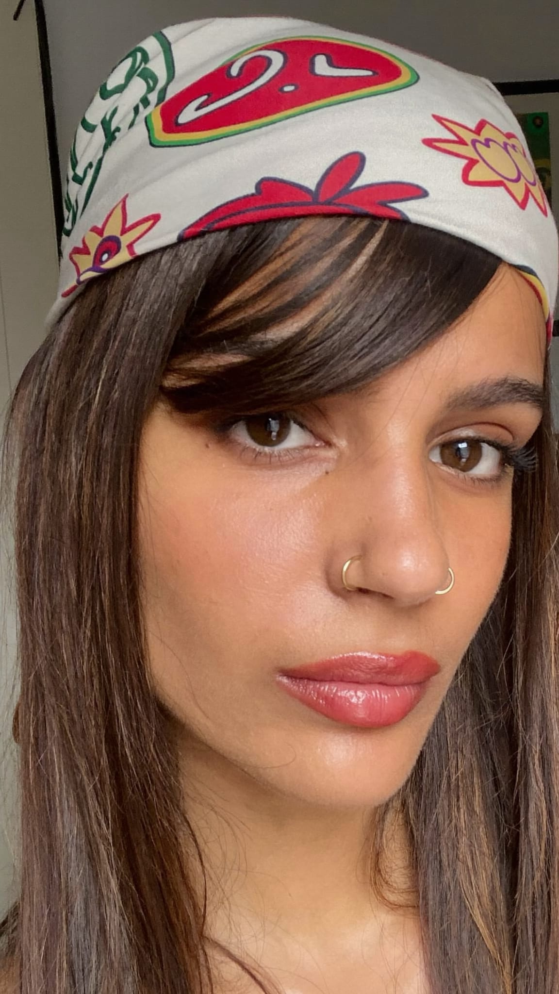 Latina woman with long side-swept bangs wearing a cotton printed bandana pushed back from her face like a headband