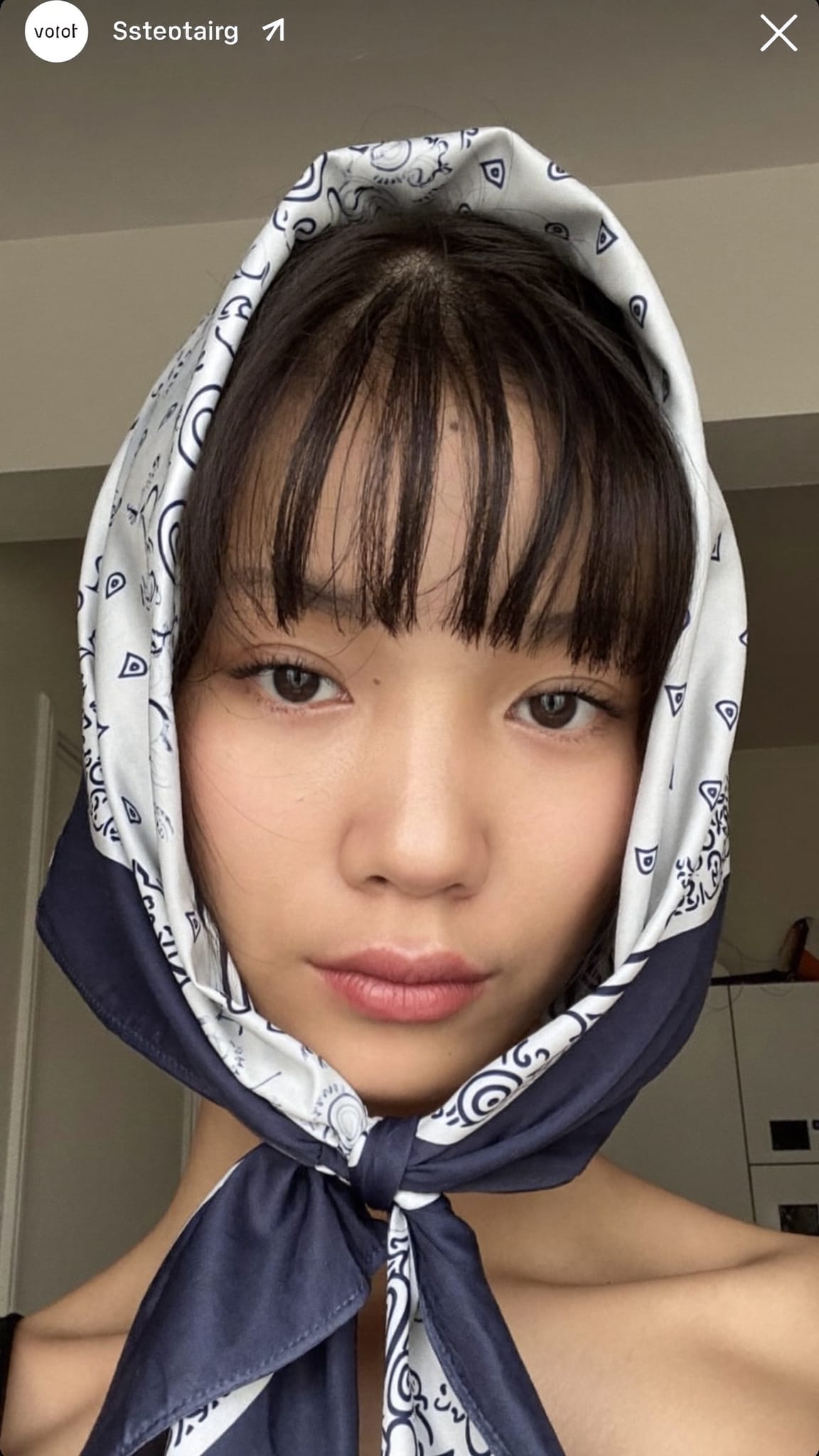 East Asian woman with middle-parted curtain bangs wearing a satin bandana knotted at the crown of her head