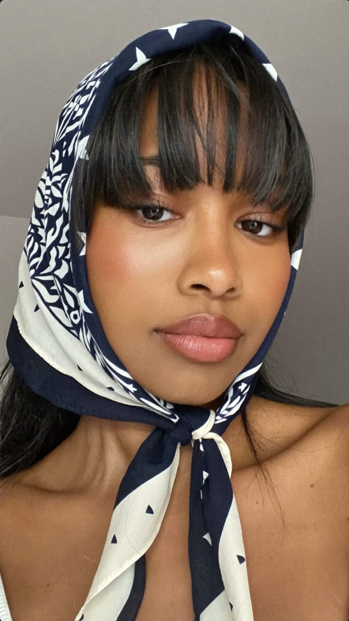 Mixed-race woman with straight fringe bangs wearing a boho triangle bandana tied in the front with fringe bangs visible below