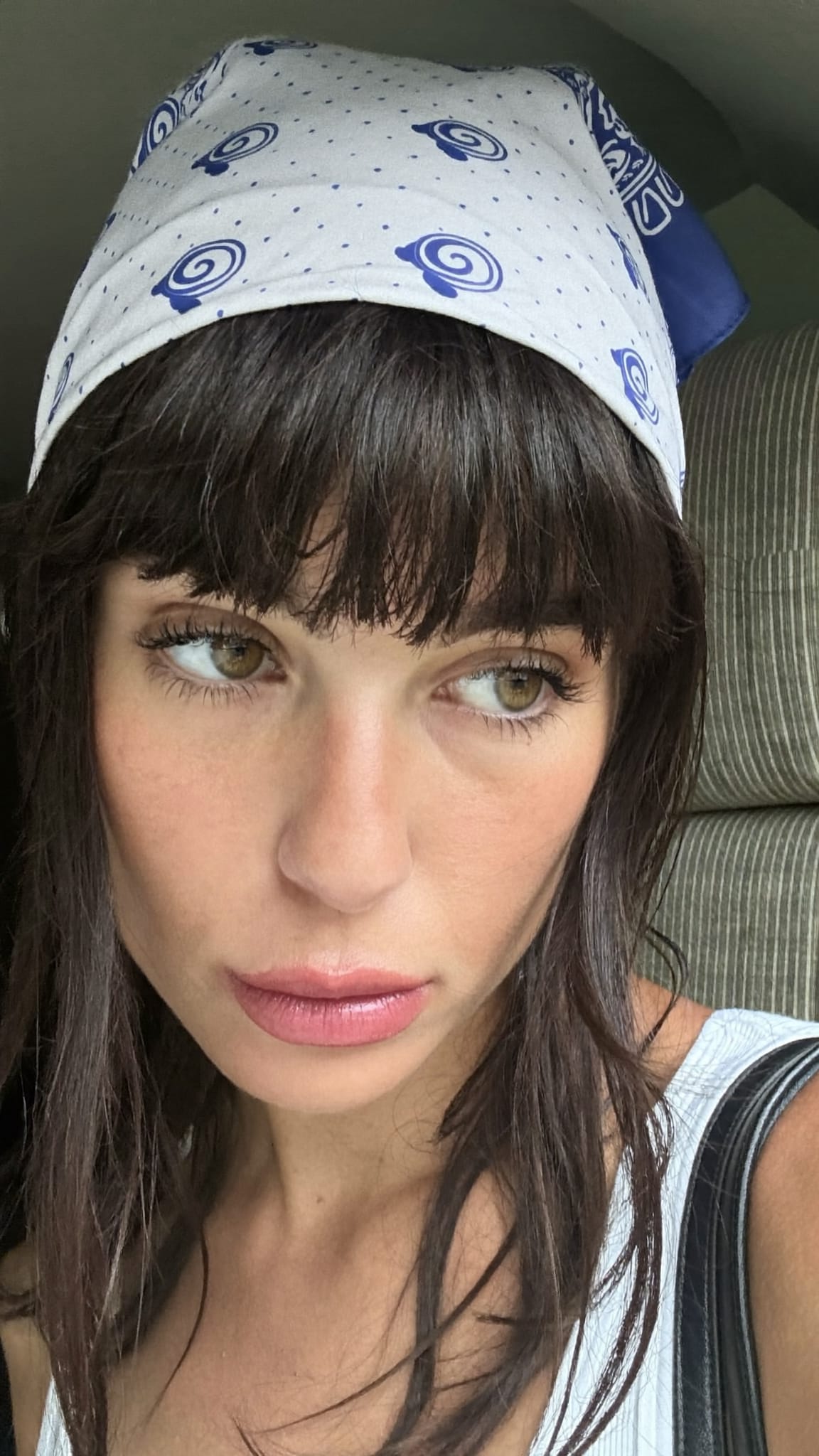 White woman with warm skin tone and choppy 70s-style fringe bangs wearing a classic paisley cotton bandana as a headband