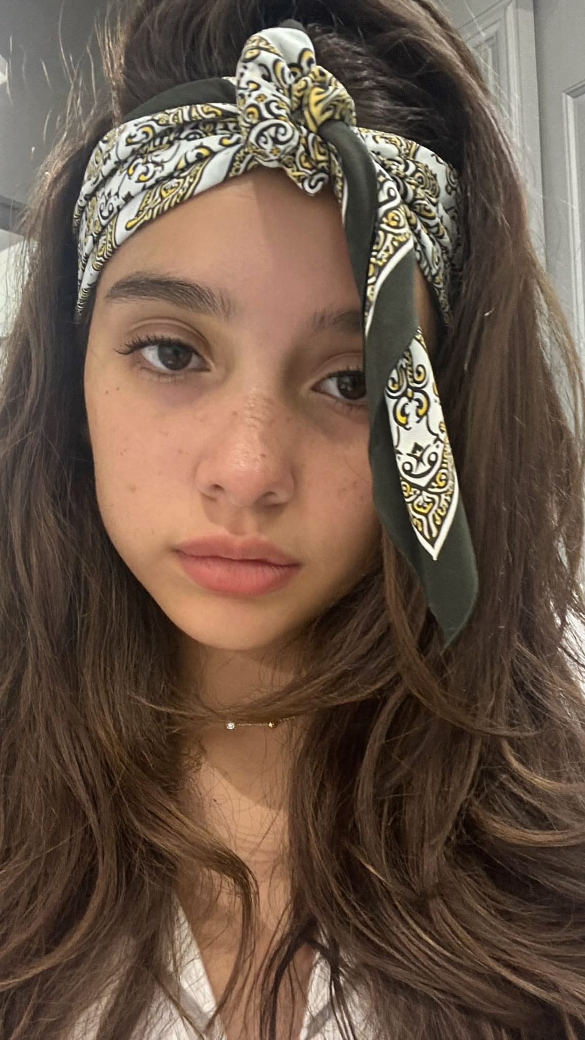 Teen girl with long hair wearing a colorful floral bandana tied as a simple elastic headband