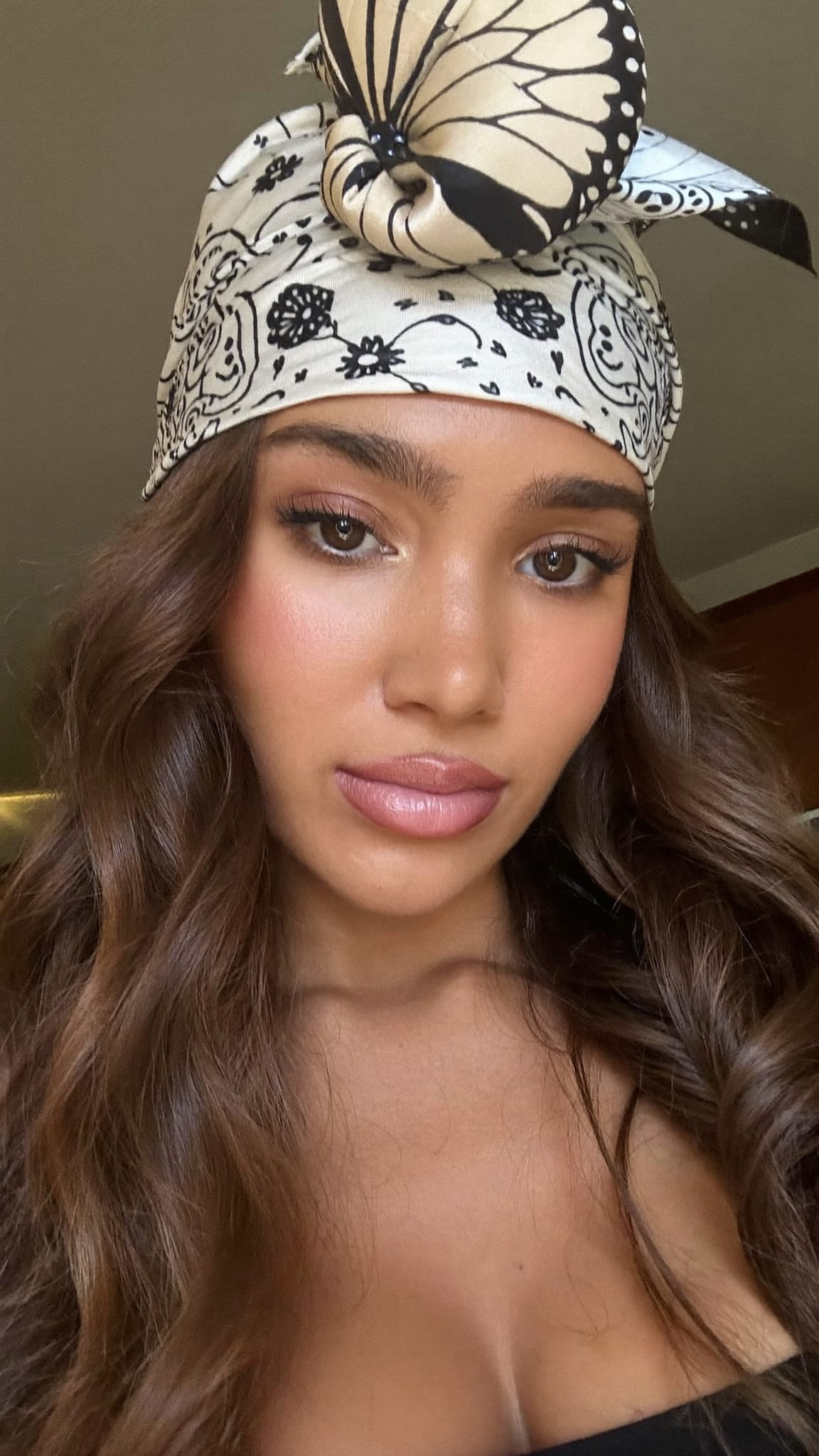 Young woman with wavy hair, a satin bandana folded and tied in a butterfly bow at the top of her head