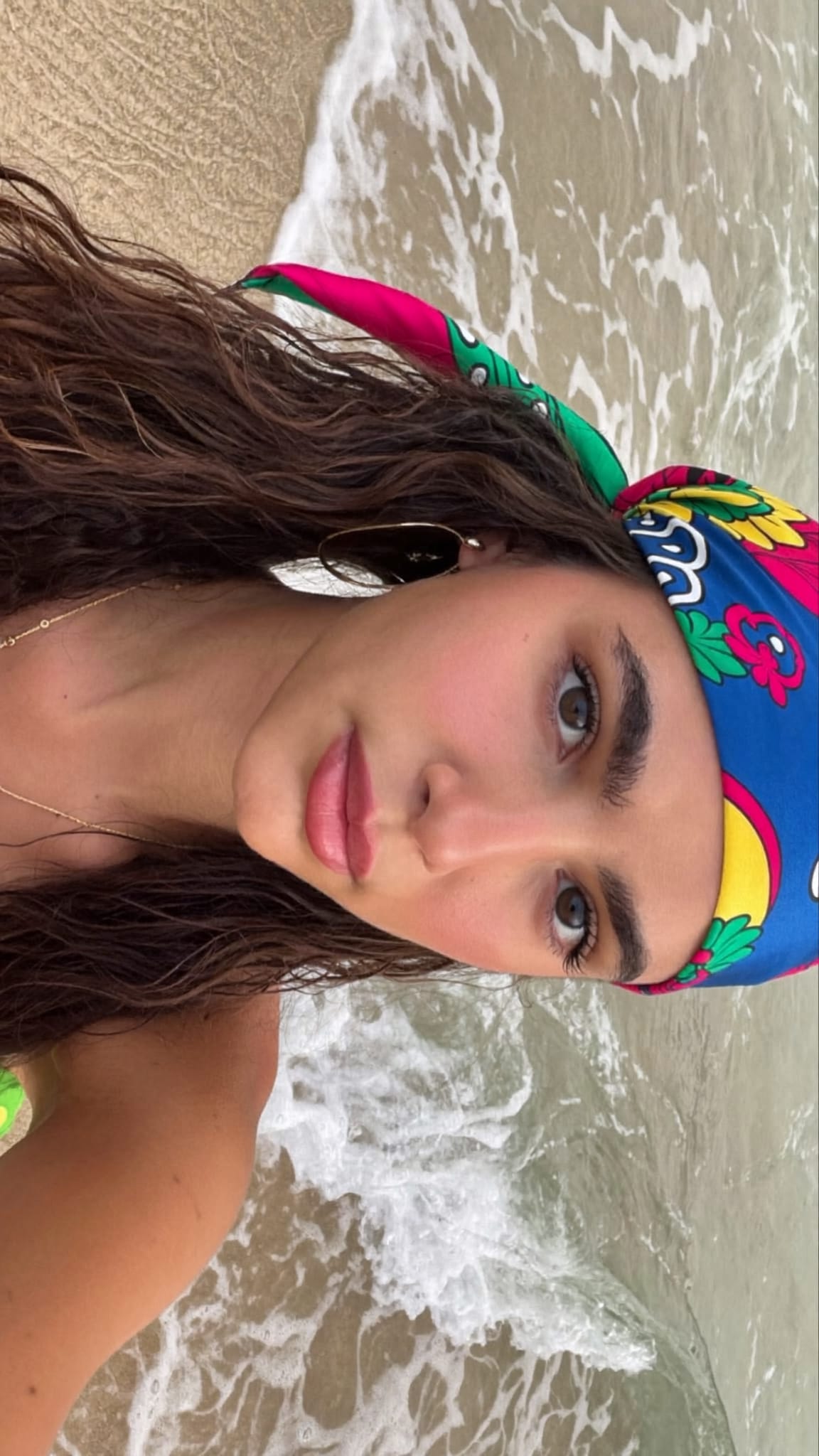 Young woman with beachy waves at the beach, a colorful satin silk-feel bandana worn as a casual headband