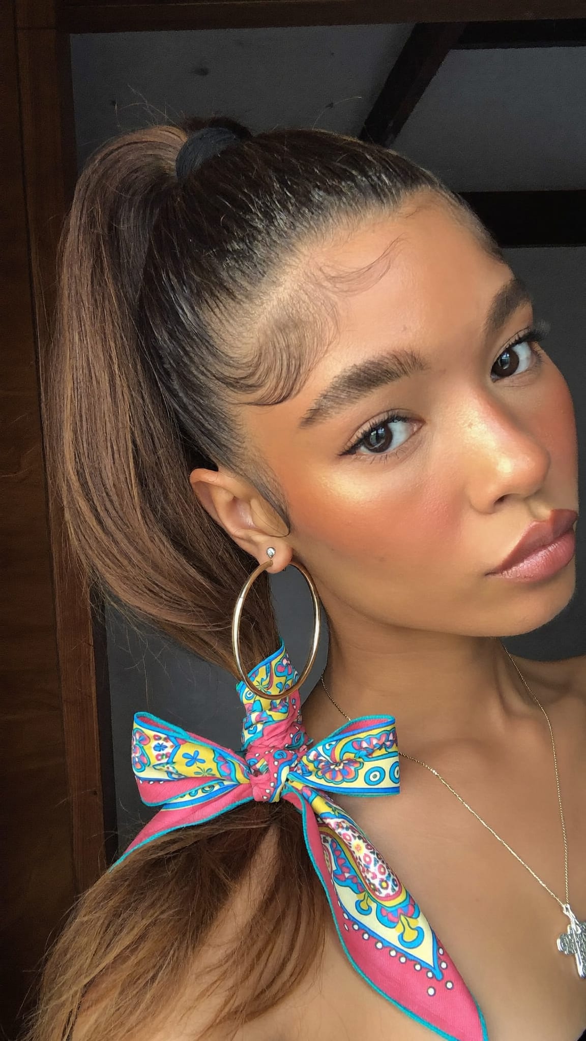 Young woman with high ponytail, a colorful satin bandana tied in a big bow around the base