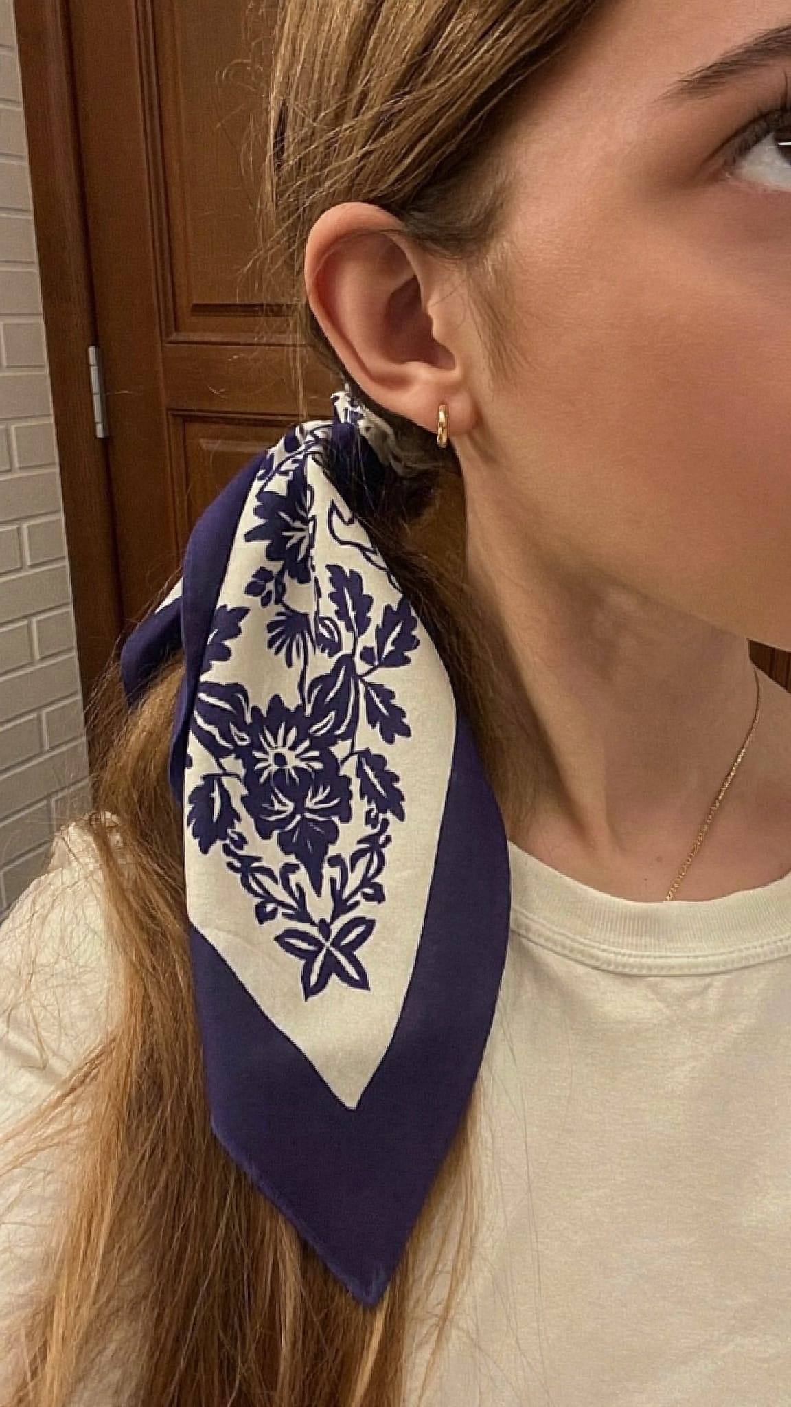Teen girl with low ponytail, a cotton floral bandana wrapped neatly around the hair tie at the nape