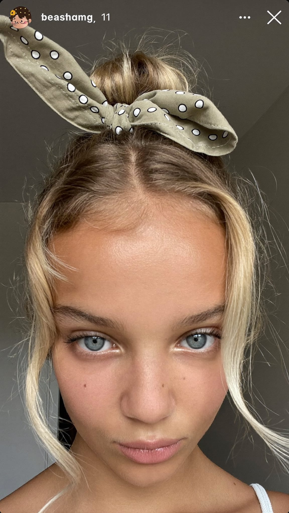Teen girl with half-up bun, a khaki boho triangle bandana tied around the bun in a cute knot