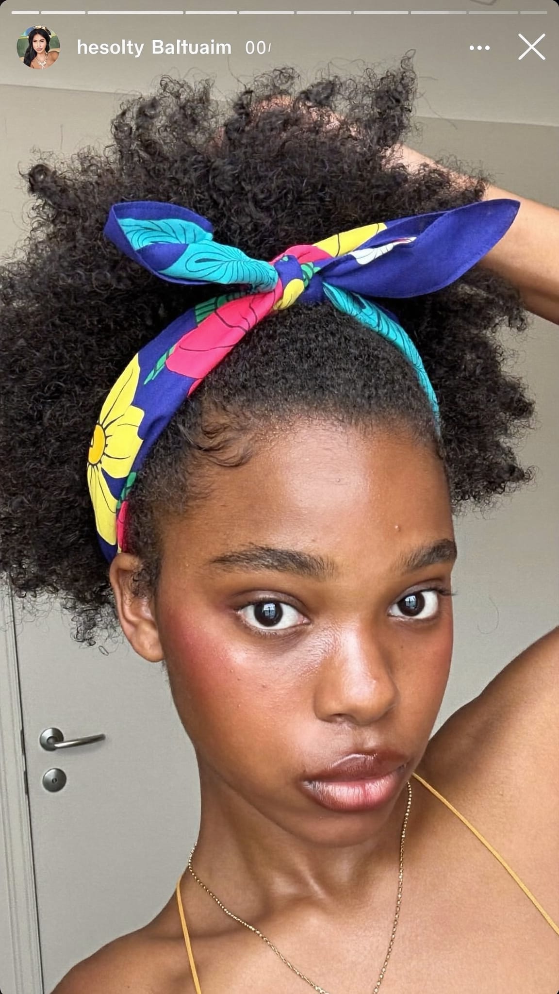 Young Black teen with natural curls wearing a colorful floral boho bandana headband pushed back on her hair