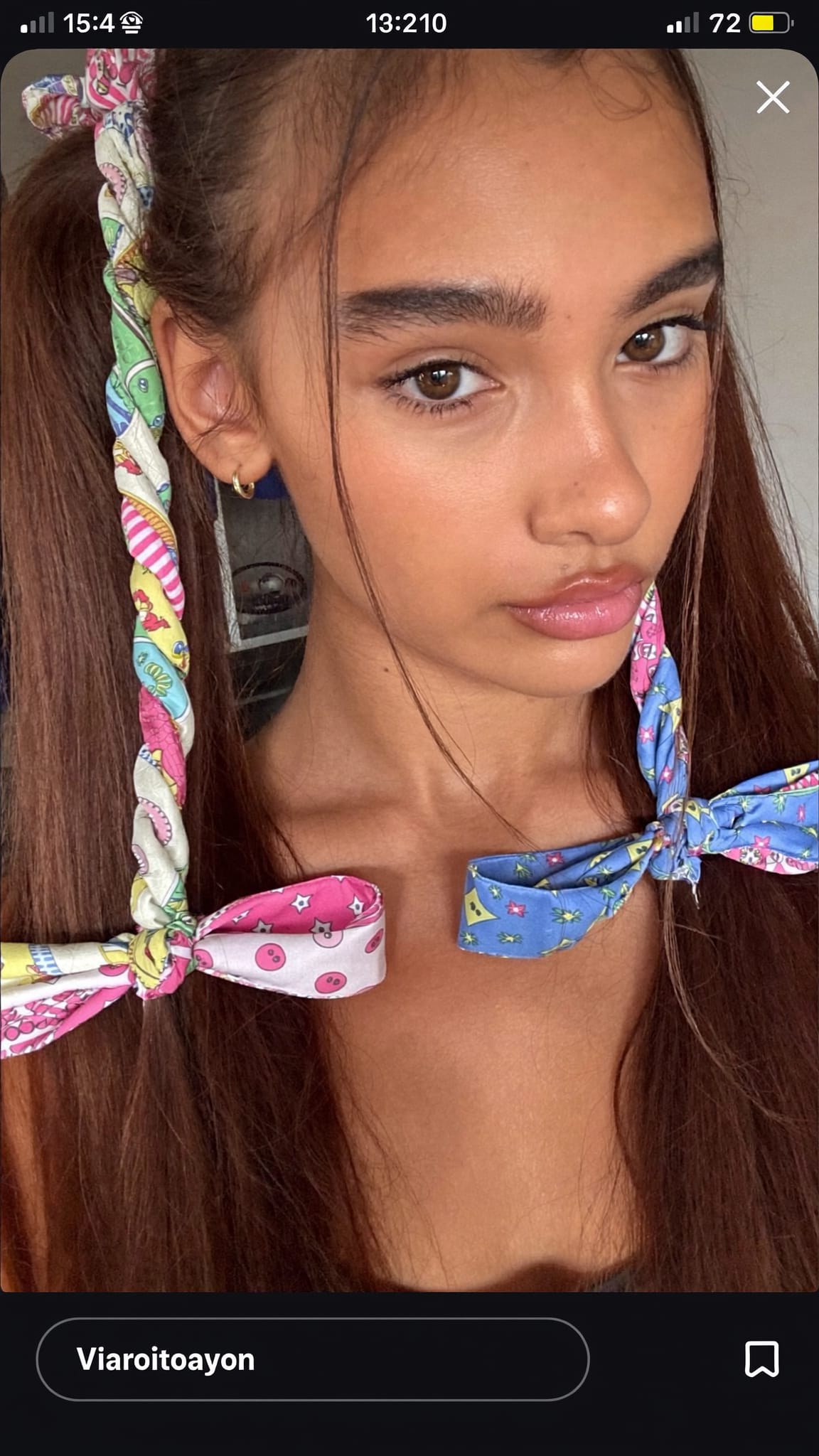 Young teen girl with two pigtails, a colorful printed bandana tied at the base of each pigtail in matching bows