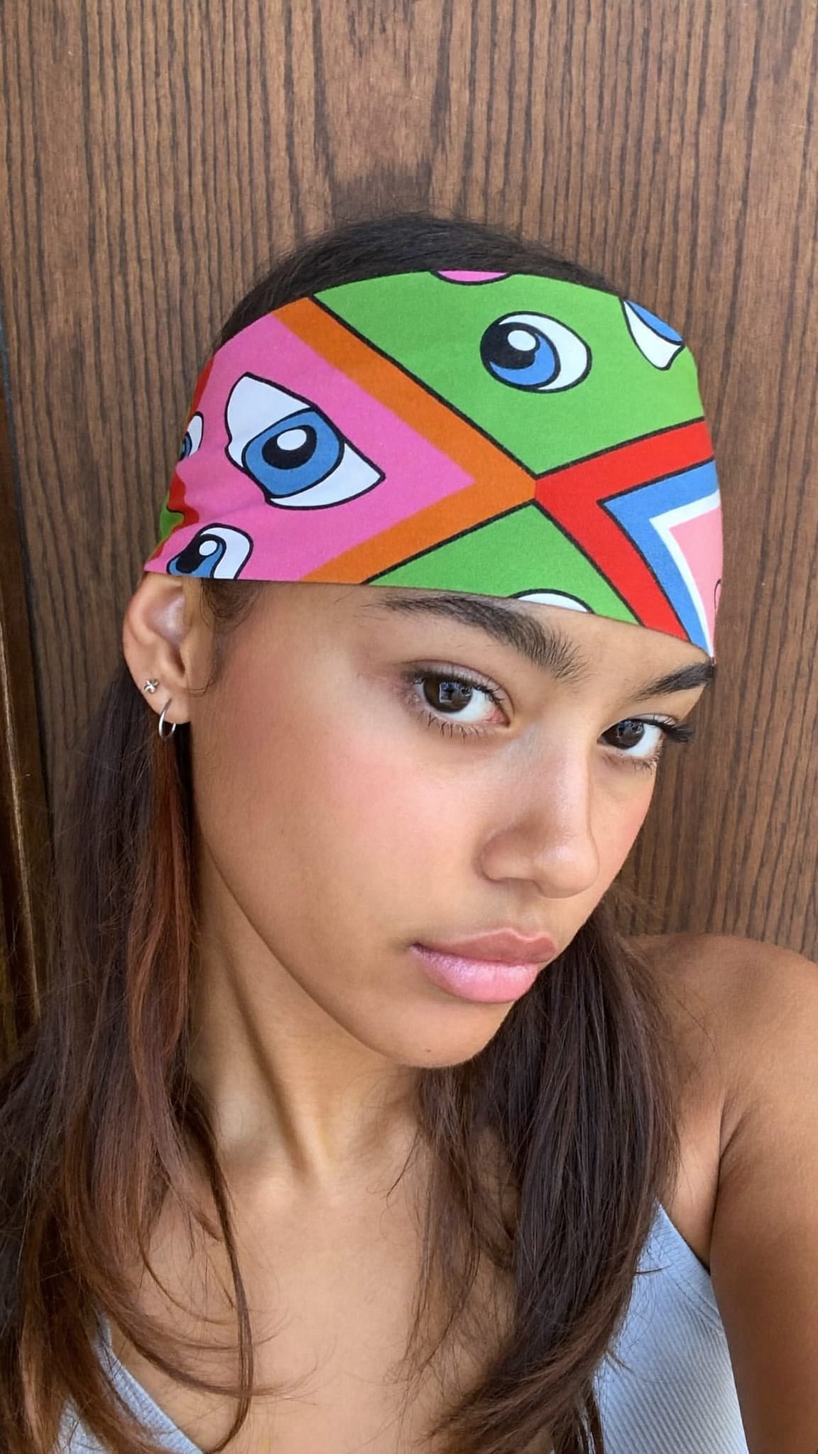 Teen girl with medium length hair, a multicolor cotton square bandana folded and worn as a push-back headband