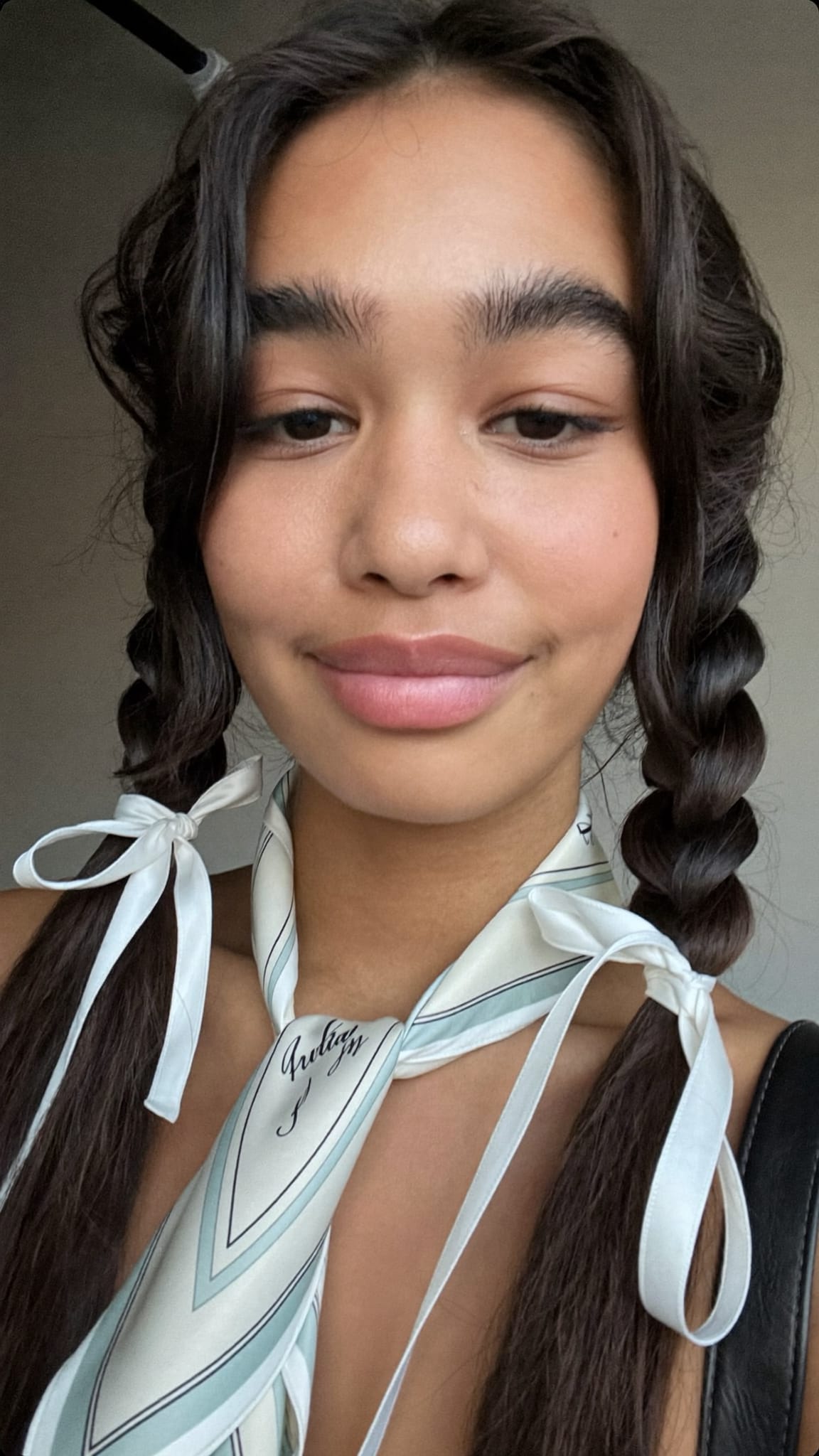 Teen girl with two braids, a skinny silk-like scarf tied in a ribbon bow at the end of each braid