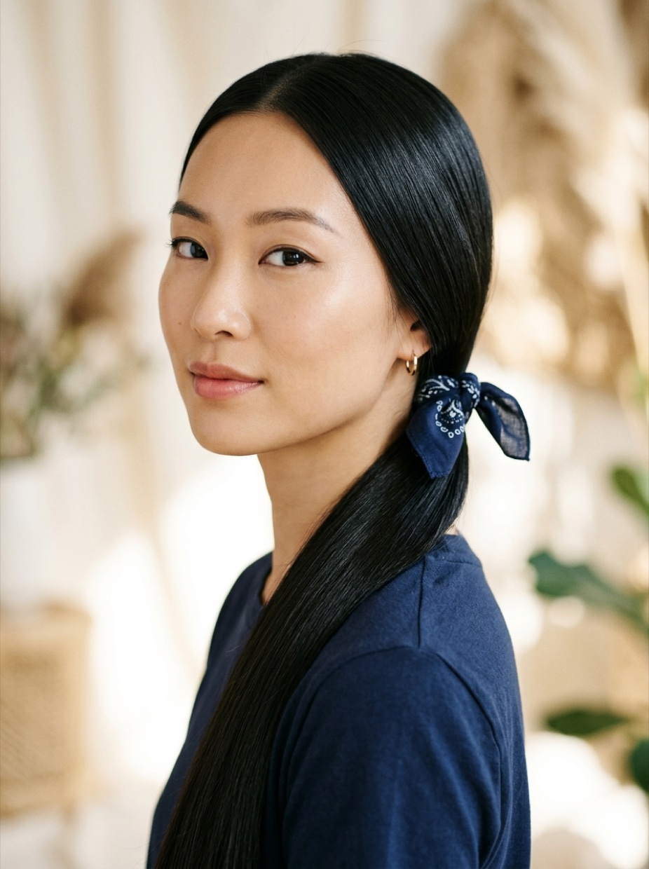 East Asian woman with long pin-straight hair in a sleek low ponytail with a navy blue cotton bandana wrapped at the base