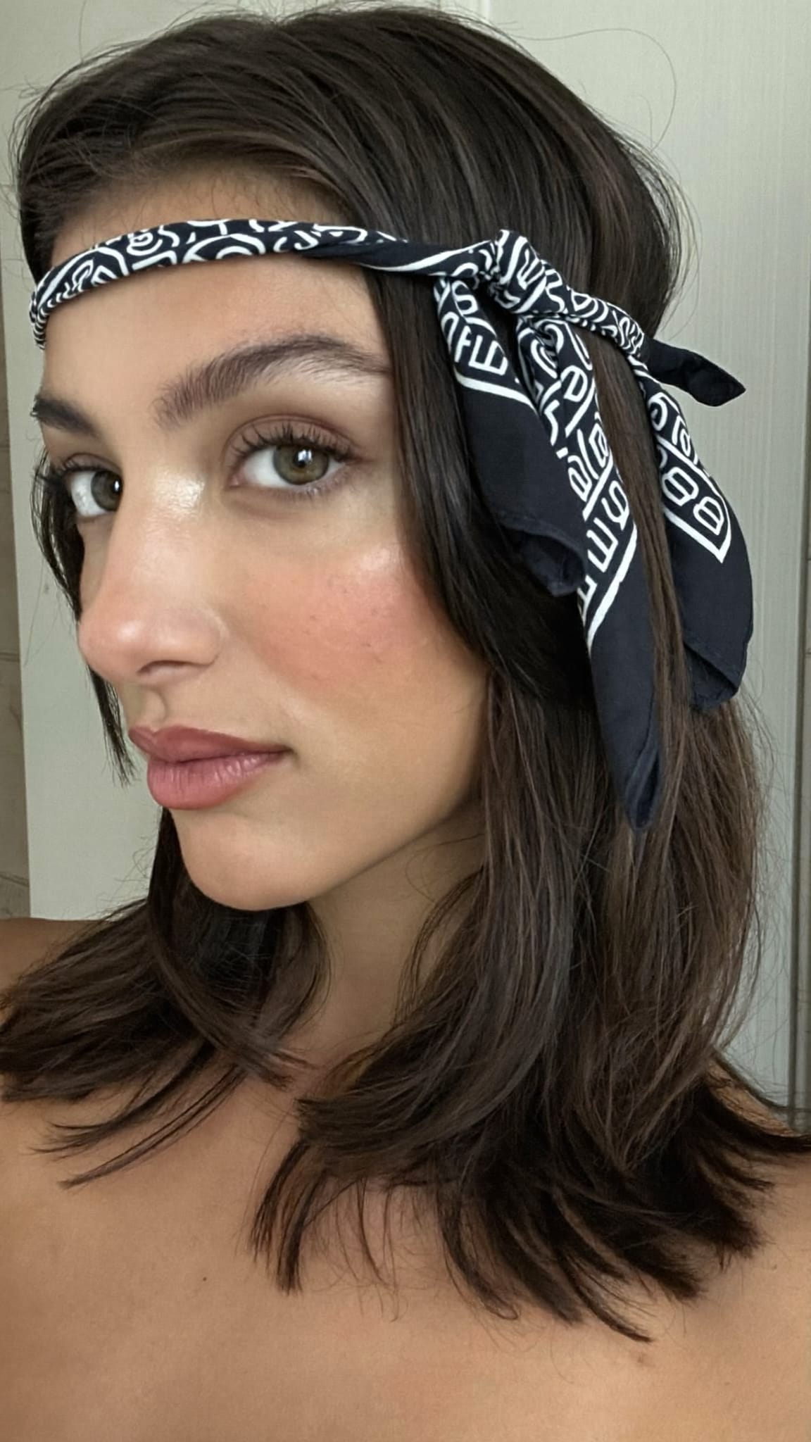 Woman with dark hair wearing a square bandana folded into a classic headband
