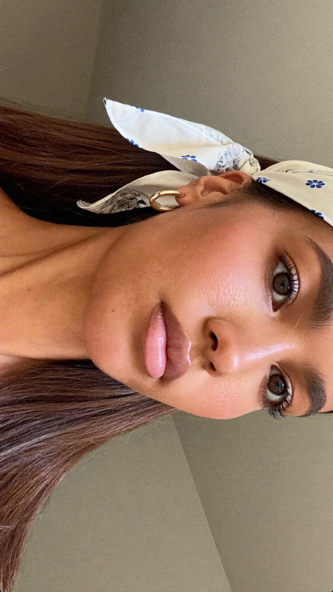 Woman with straight brown hair wearing a floral bandana tucked behind both ears as a French wrap headband