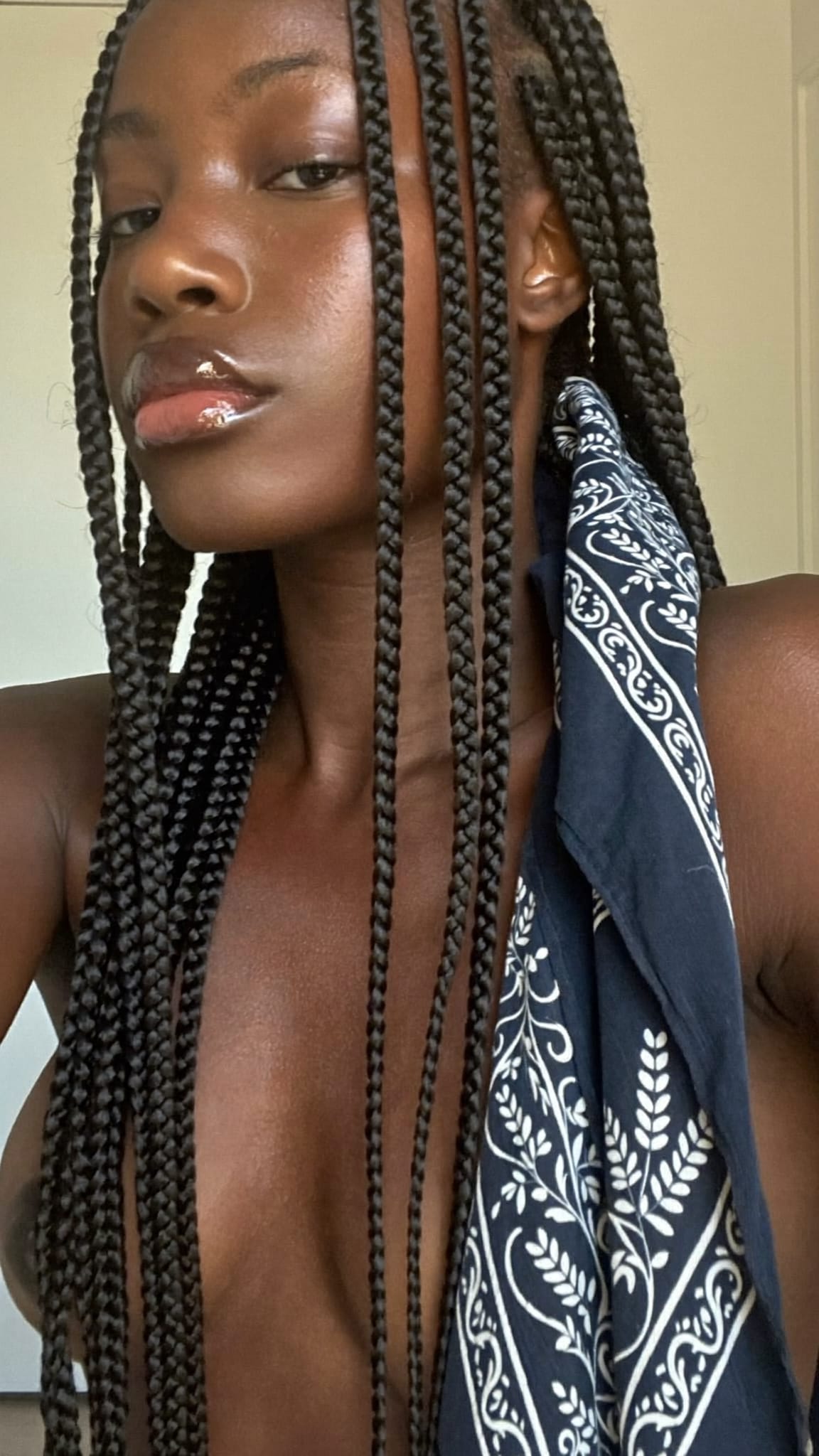 Black woman with dark skin and long box braids with a navy blue floral bandana woven through one braid
