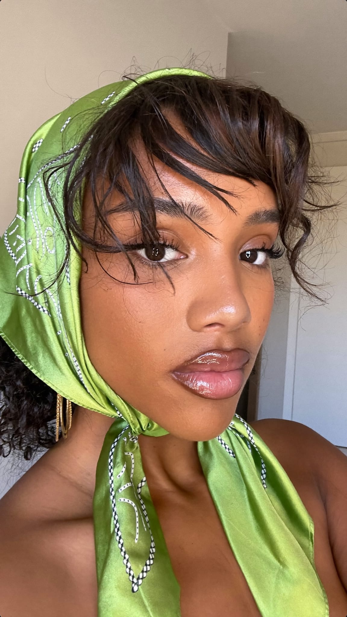 Young woman with warm brown skin and a wavy bob with a green satin bandana tied in a double knot at the nape