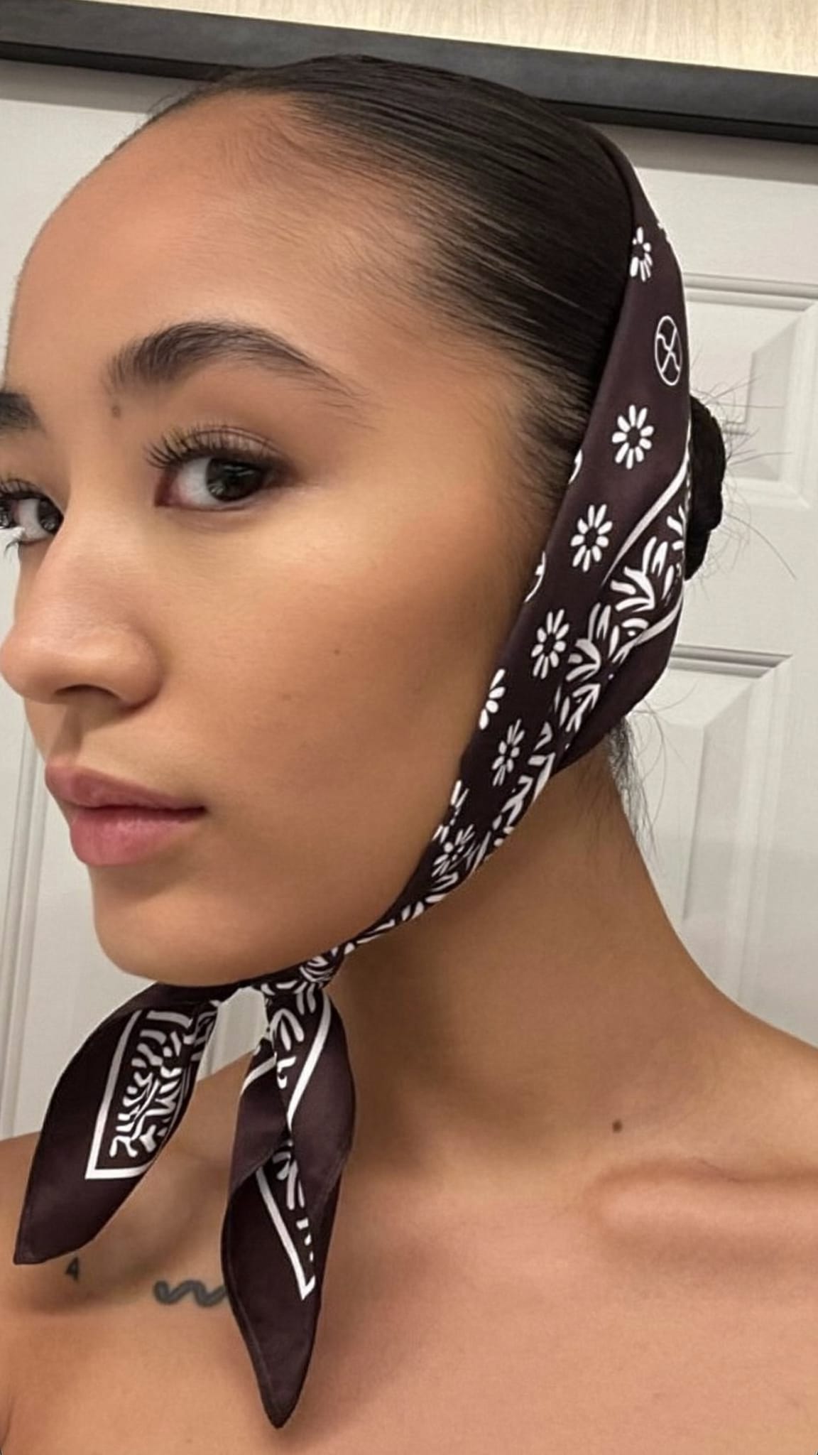 East Asian woman with a sleek low bun and a satin bandana worn over the ears as an accent headband