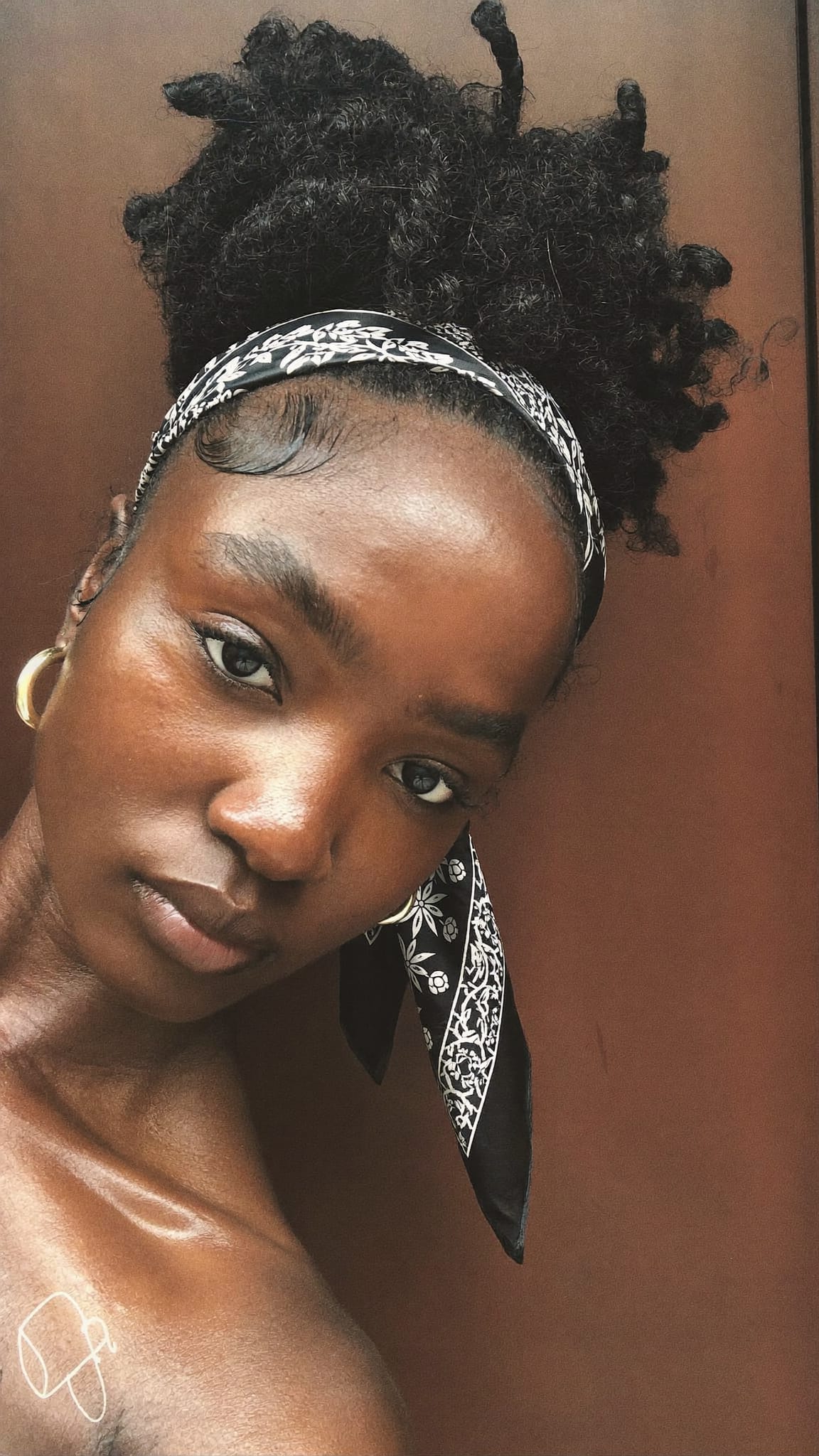 Black woman with natural 4C hair in a high puff ponytail with a satin silk-like bandana tied at the base
