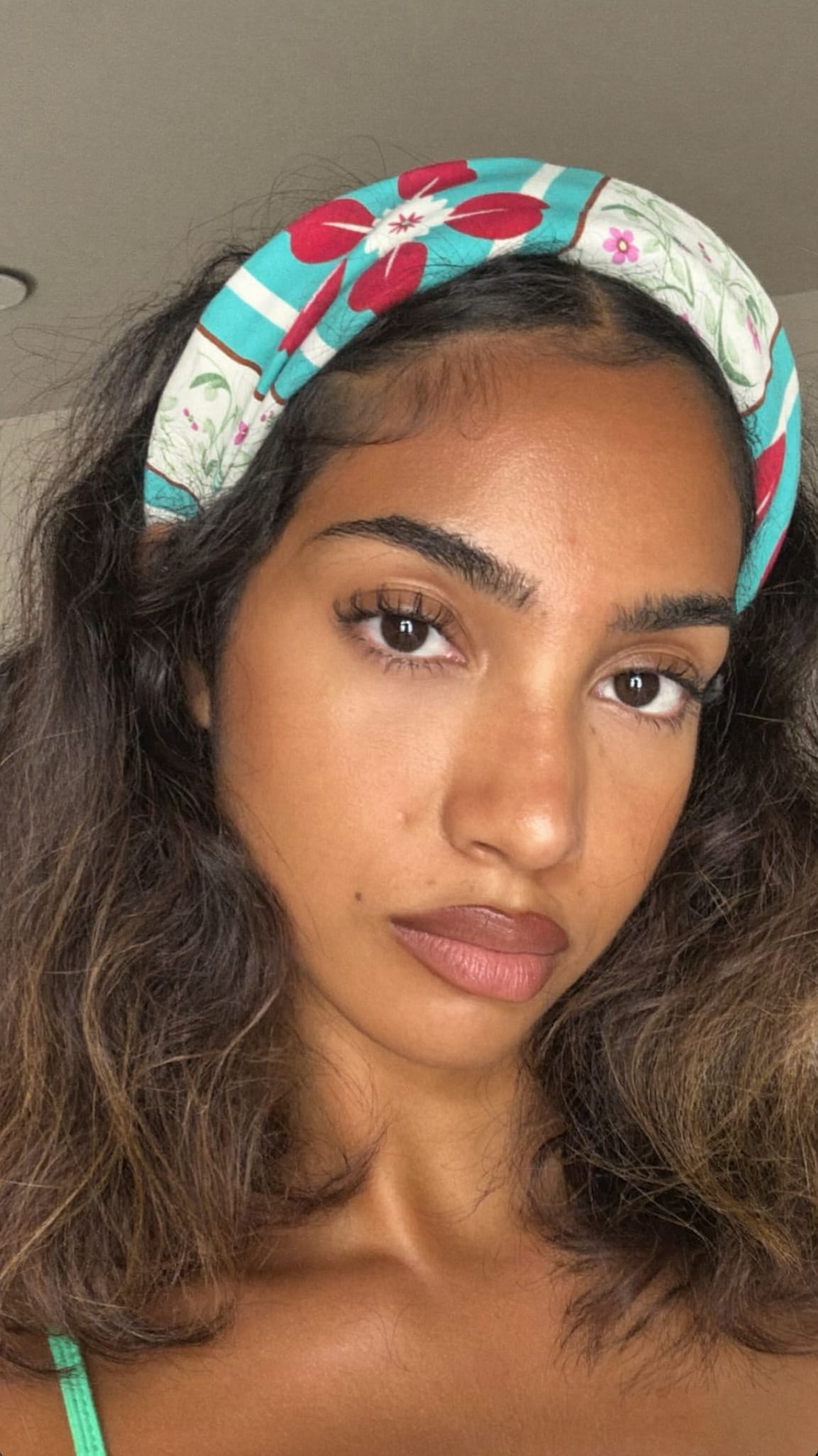 South Asian woman with warm skin tone and shoulder-length wavy hair wearing a boho floral bandana headband tucked behind the ears