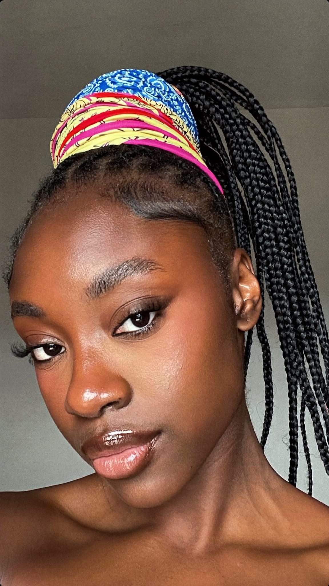 Black woman with natural hair in a high ponytail wrapped with a colorful cotton bandana