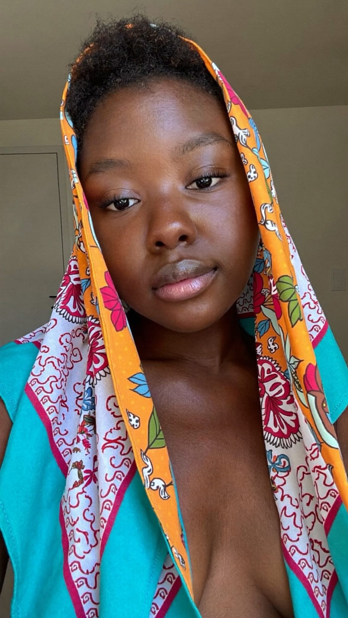 Black woman with short natural hair wearing a multicolored cotton bandana draped do-rag style