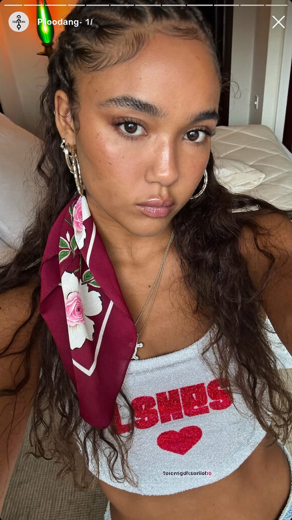 Latina woman in her 20s with crimped textured hair and a floral bandana half-wrap at the hairline, wearing a sparkly crop top in a Y2K bedroom with a lava lamp